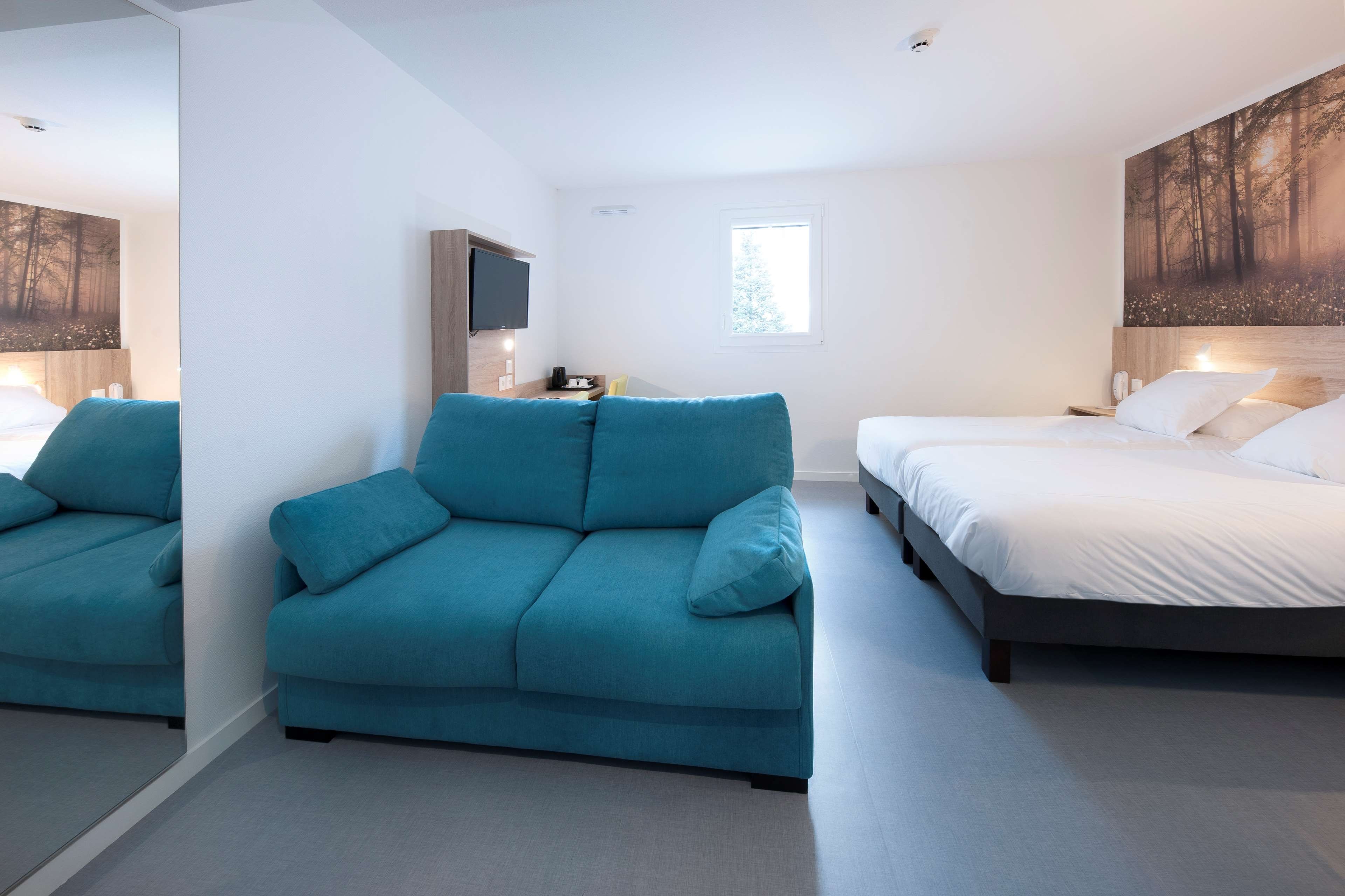 Ein modernes Schlafzimmer mit einer Couch, einem Bett, einem Fernseher und Kunstwerken an den Wänden.