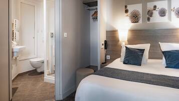 Ein Hotelzimmer mit Bett, Nachttisch, Lampe und einem Bild an der Wand.