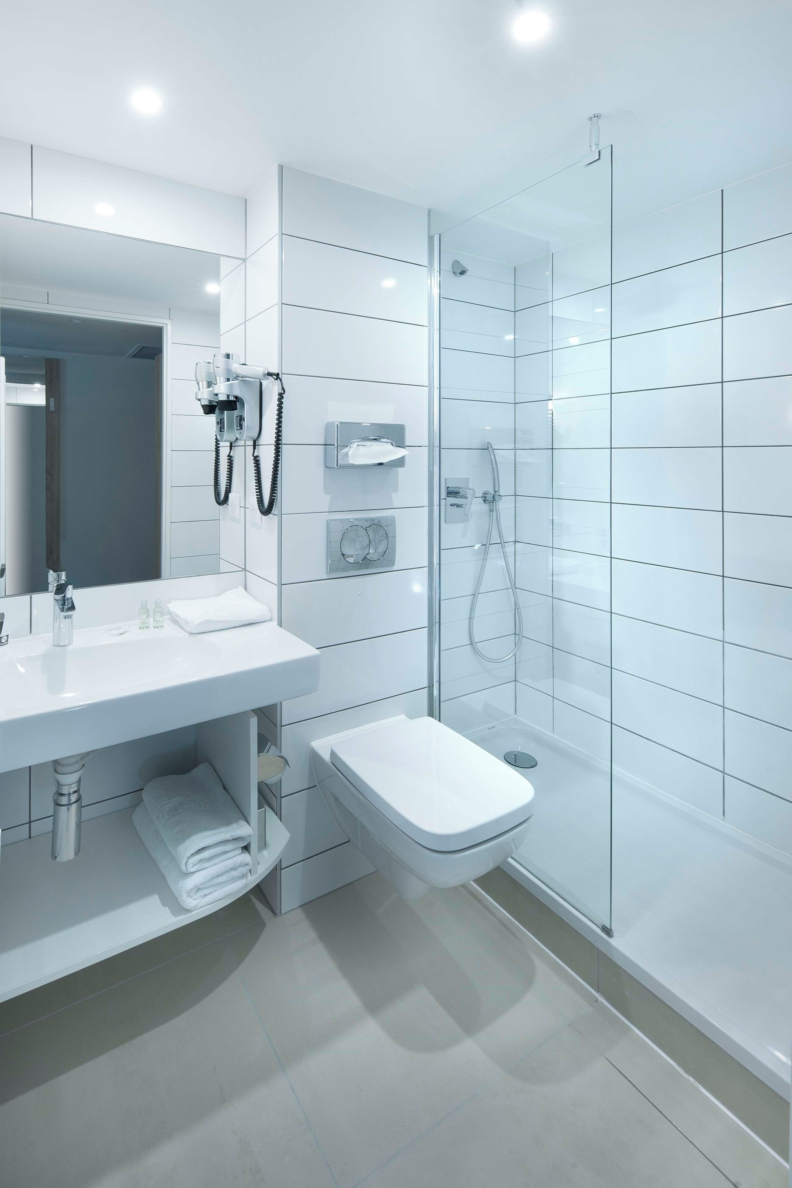 Un baño moderno con cabina de ducha de vidrio, lavamanos blanco y un inodoro.
