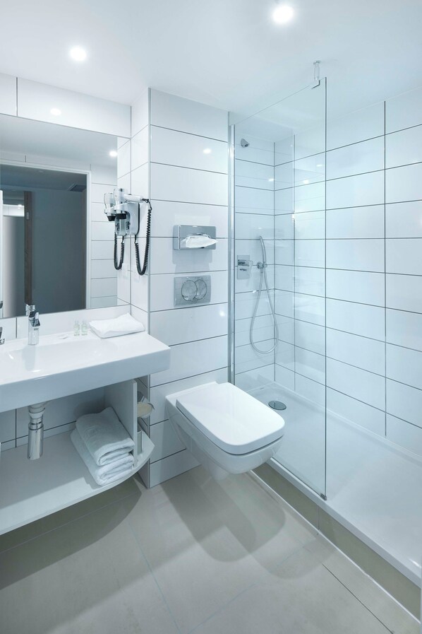 A modern bathroom with a glass shower enclosure, a white sink, and a toilet. - Kyriad Annemasse - Genève (Annemasse)