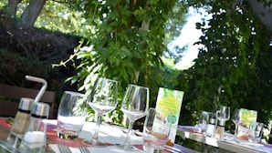 Une table dressée à l’extérieur, avec des verres à vin, un menu et des salières et poivrières.
