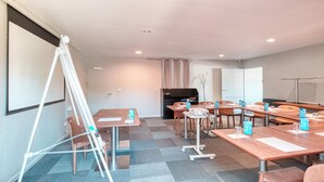 A conference room with a projector, tables, chairs, and a TV screen.