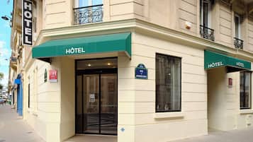 A hotel with a green awning, a sign indicating the address, and a visible entrance.