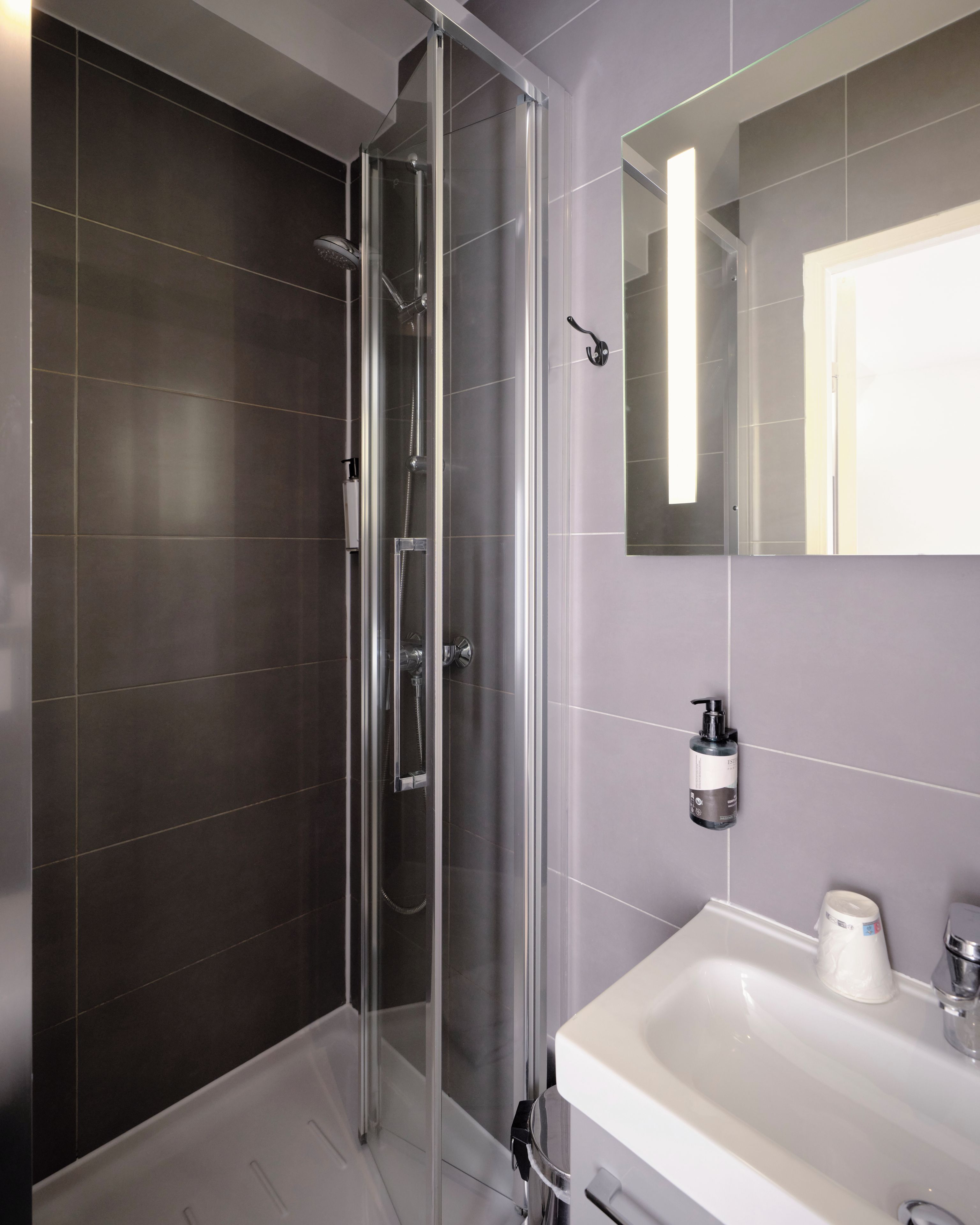 A modern bathroom with a glass-enclosed shower, a white sink, and a mirror.