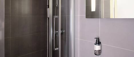 A modern bathroom with a glass-enclosed shower, a white sink, and a mirror.