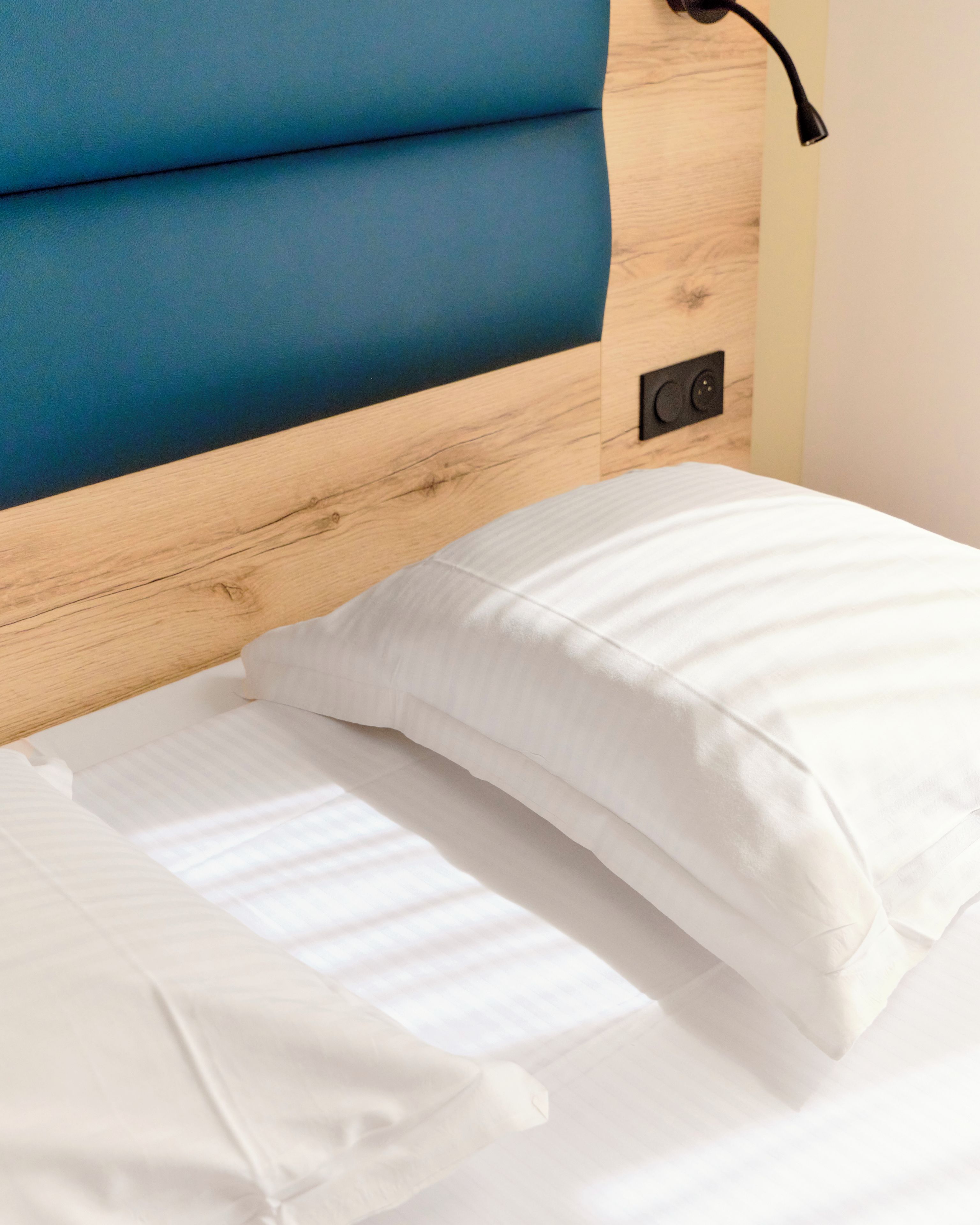 Una cama con ropa de cama blanca y cabecera azul.