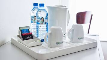 A tray with two water bottles, a coffee maker, a mug, and a card holder with a card.