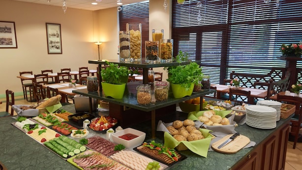 Una mesa con cubierta de vidrio exhibe una barra de buffet con diversos alimentos y plantas en macetas verdes.
