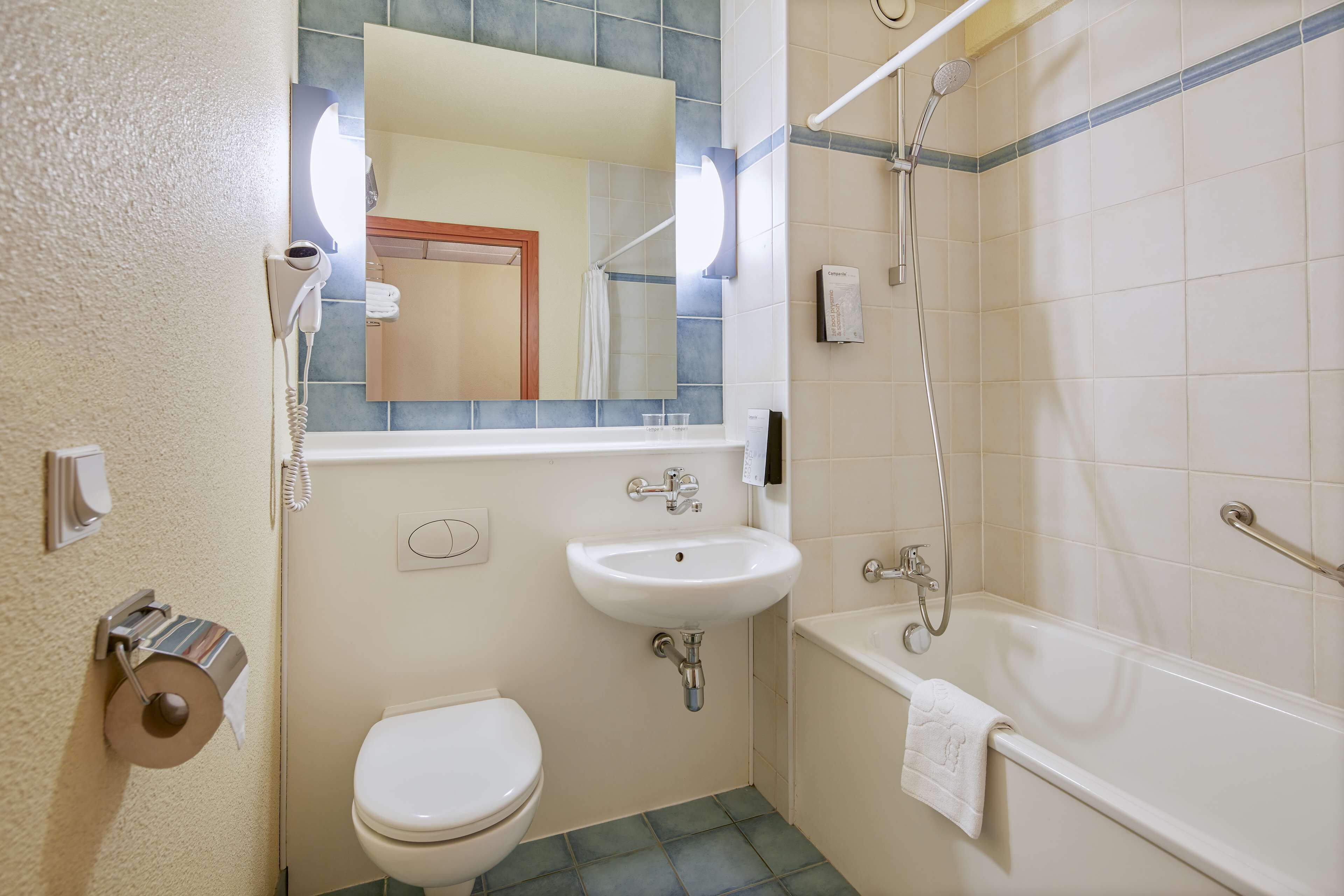 Et badeværelse med toilet, vask og badekar.