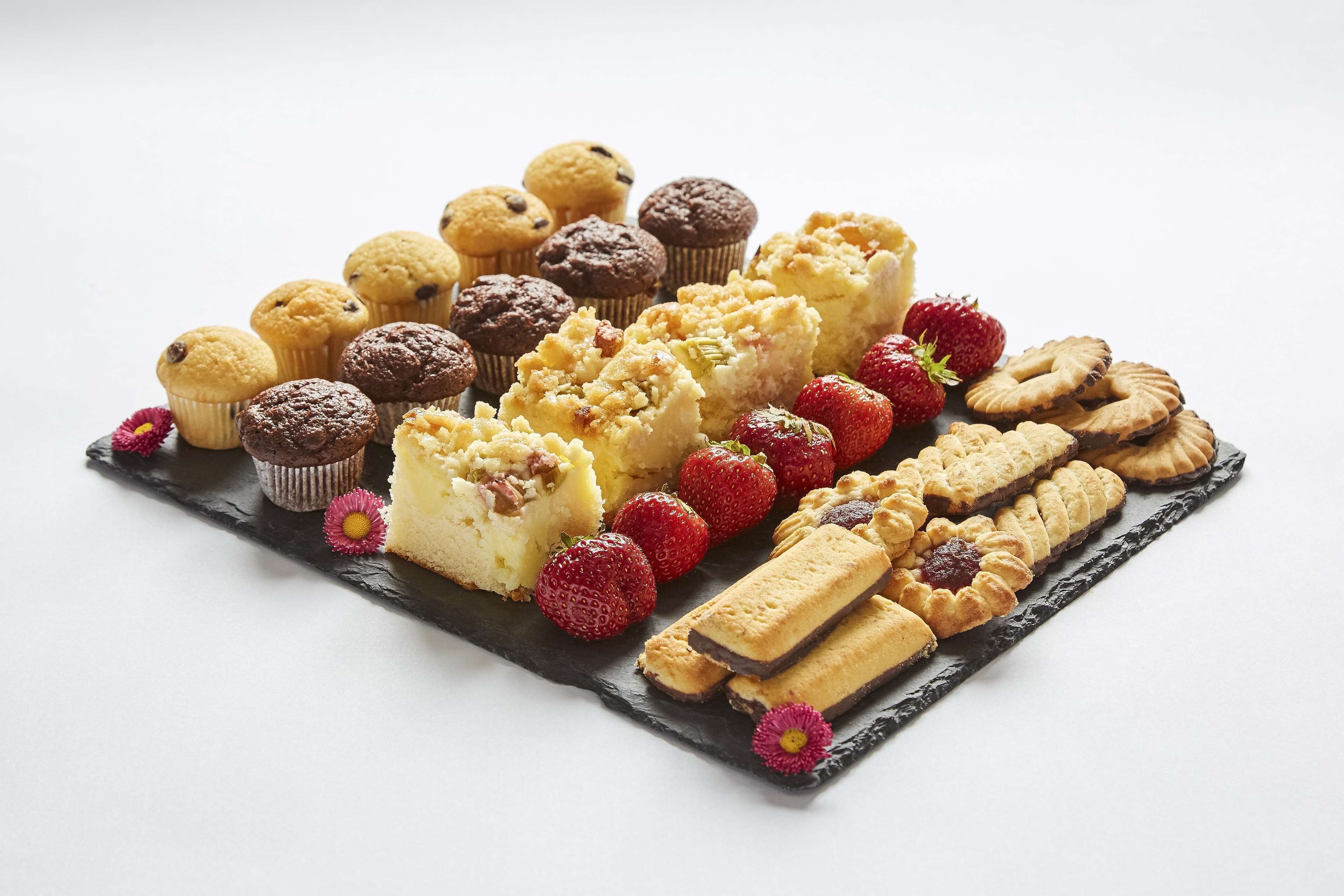 A variety of pastries and cookies arranged on a slate serving board.