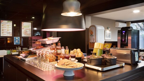 Mostrador de buffet con diferentes opciones de comida, una máquina de café y un tostador.