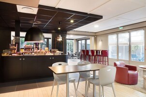 A modern kitchen area with a central island, white chairs, and red seating.