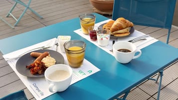 Una mesa con alimentos para el desayuno, incluyendo cruasanes, un plato de comida, un vaso de jugo, una taza de café y un tazón de sopa.