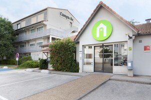 A modern building with a 'Camparille' sign, a green logo, and a glass entrance.