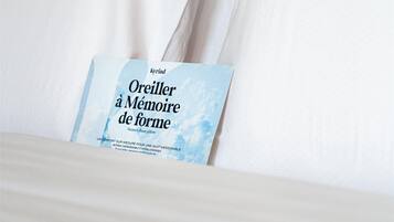 En pænt redt seng med hvide sengetøj og en bog med titlen "Orelier à Mémoire de forme" placeret ovenpå.