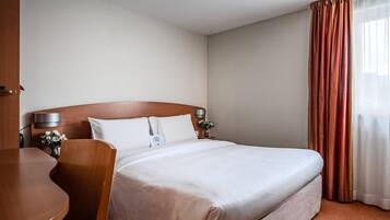 Une chambre d’hôtel avec un grand lit, un bureau en bois et une chaise.