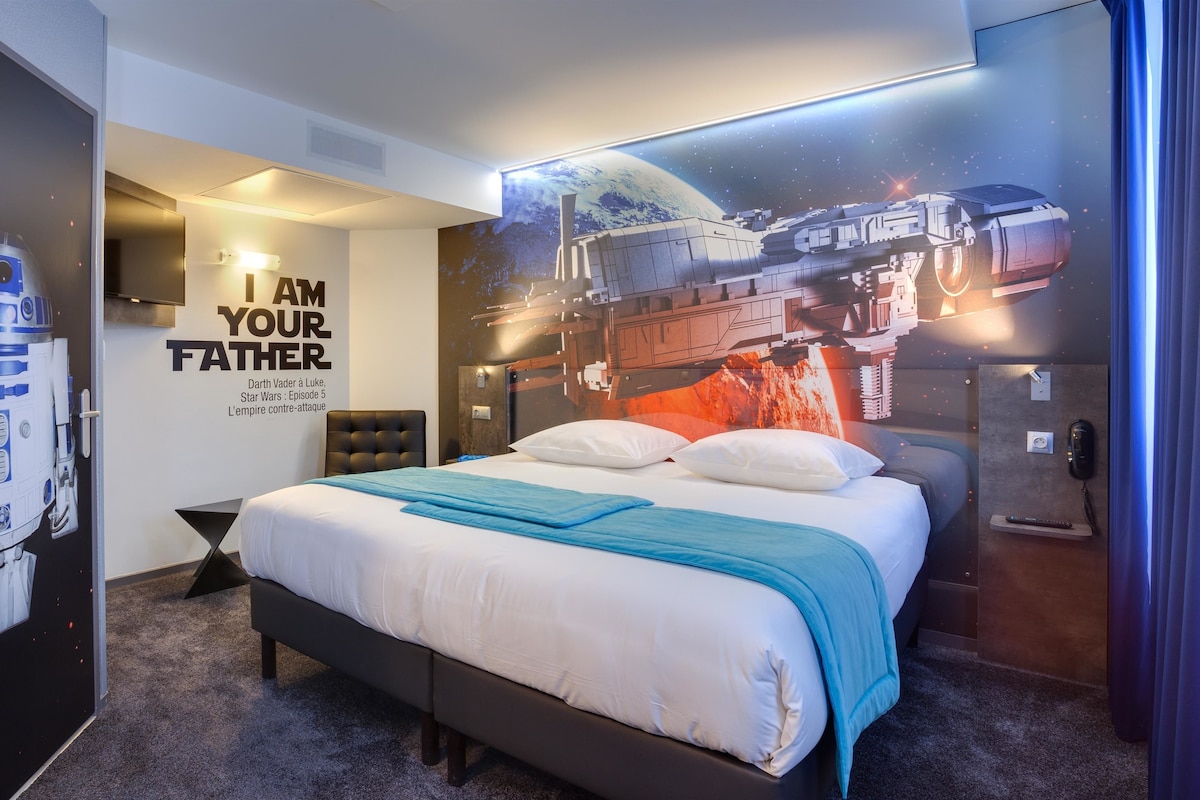 A Star Wars-themed bedroom with a bed, pillows, a wall mural, and a poster of R2-D2.