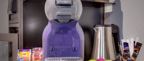 A coffee machine with a purple and white design, a coffee pot, and various coffee pods and containers on a counter.