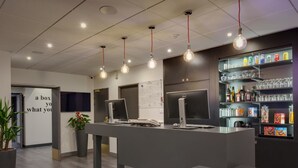 Una moderna zona de recepción con un mostrador, computadora y una estantería con bebidas y aperitivos.