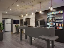 Un espace d’accueil moderne comprenant un comptoir, un ordinateur et une étagère avec des boissons et des collations.