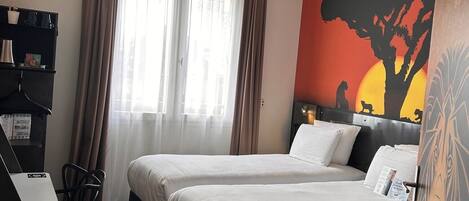 A hotel room with two beds, a desk, and a large wall mural.