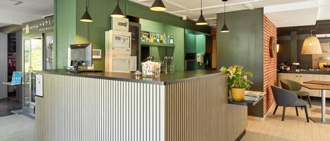 Una cocina moderna con paredes verdes, una isla central con lavamanos e iluminación colgante.