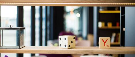 A wooden shelf with dice and letters, a glass container, and a purple cushion.