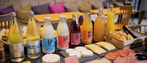 Un bufé de desayuno con diversos quesos, embutidos y jugos.