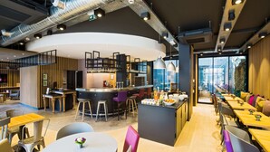 Zona de bar moderna con taburetes, una barra y vistas de la ciudad a través de amplias ventanas.