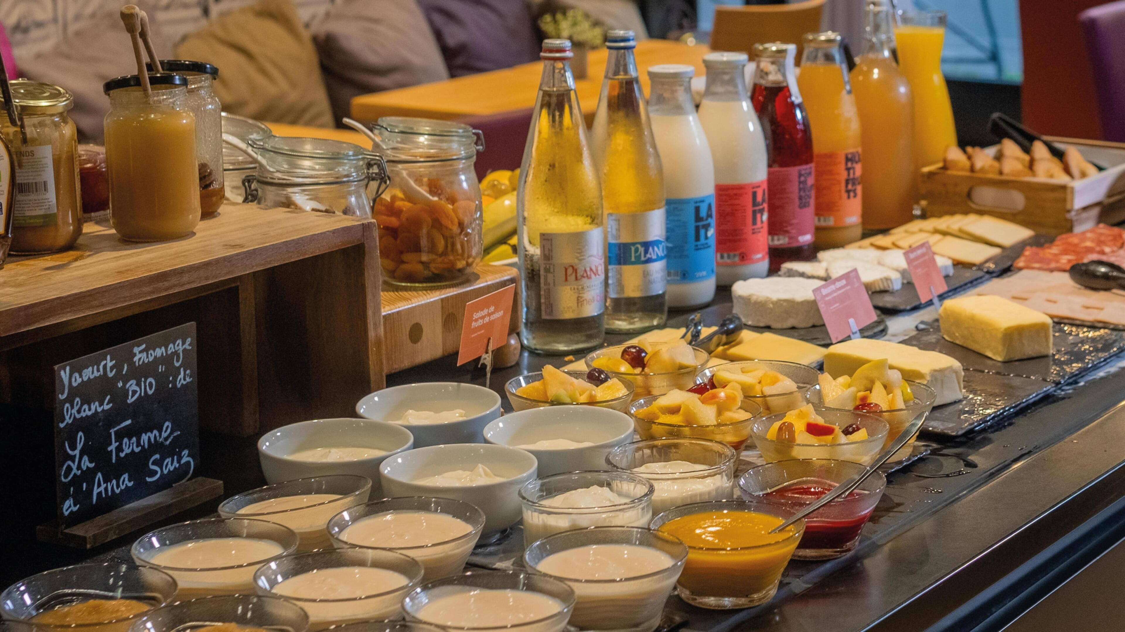 A buffet with various food items, including fruits, cheeses, and beverages.
