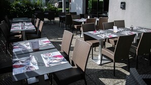 Un área de comedor al aire libre con mesas y sillas, algunas con menús y vasos.