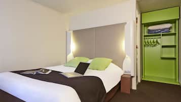 Une chambre d’hôtel avec un lit, un ordinateur portable et un meuble de rangement vert.