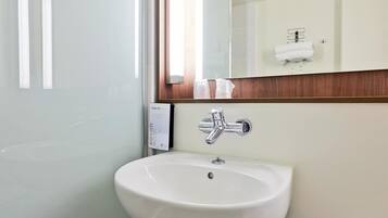 Une salle de bain avec un lavabo blanc, un miroir et un porte-serviettes.
