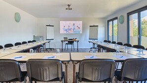 A conference room with long tables, chairs, a projector screen, and a presentation on the wall. - Kyriad Direct Strasbourg Ouest - Zénith (Strasbourg)
