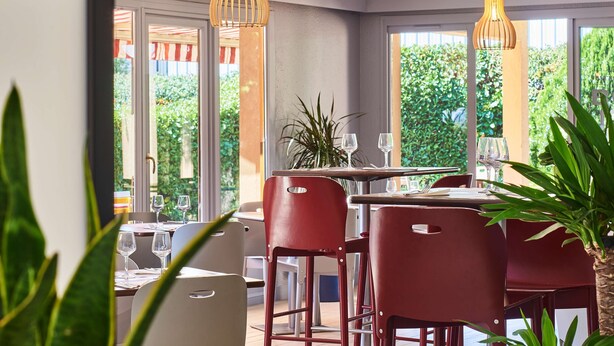 An indoor dining area with red chairs, a table set with wine glasses, and hanging pendant lights. - Kyriad Direct Strasbourg Ouest - Zénith (Strasbourg)