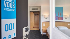 A hotel room with a bed, a desk, and a wardrobe. There is a sign on the wall that says "Bienvenue Chez Vous Welcome Home." - Kyriad Direct Strasbourg Ouest - Zénith (Strasbourg)