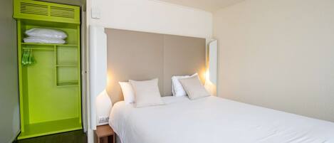 A hotel room with a large bed, a green wardrobe, and a bedside table.