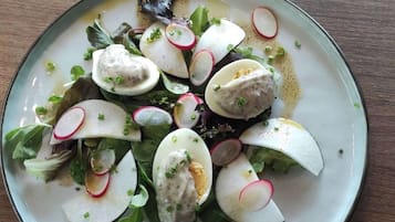 A plate of food with boiled eggs, radishes, and greens on a wooden table.