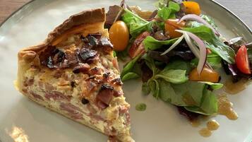 A plate with a slice of quiche and a mixed green salad.