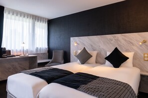Een moderne hotelkamer met een groot bed, nachtkastjes, een bureau en een stoel.