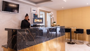 Ein moderner Empfangsbereich mit Marmor-Theke, Flachbildfernseher, digitalem Thermostat und einer Topf-Orchidee.