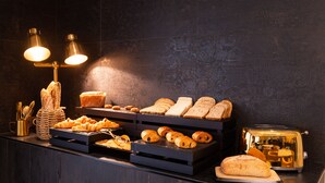Ein Frühstücksbuffet mit verschiedenen Brotsorten, Gebäck und einem Toaster.