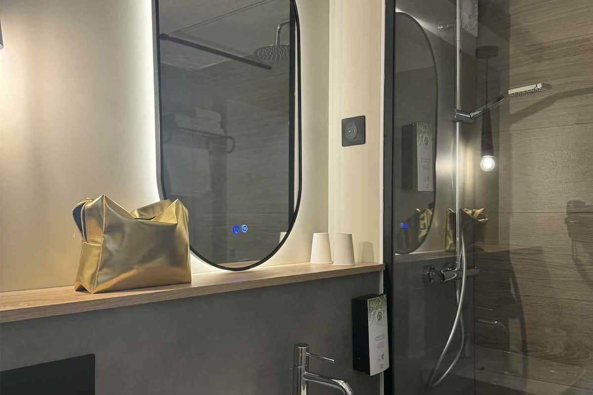 A modern bathroom with a white sink, a large mirror, and a glass shower enclosure.