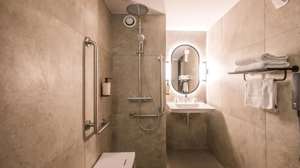 Ein modernes Badezimmer mit Dusche, Toilette, Waschbecken und Handtuchhalter.
