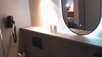 Een moderne badkamer met toilet, wastafel en spiegel.