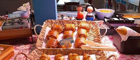 Un bufé de desayuno con pastelería y un menú en la pizarra.