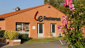 Un restaurante con un letrero que indica que es un local nuevo y una señal de estacionamiento.