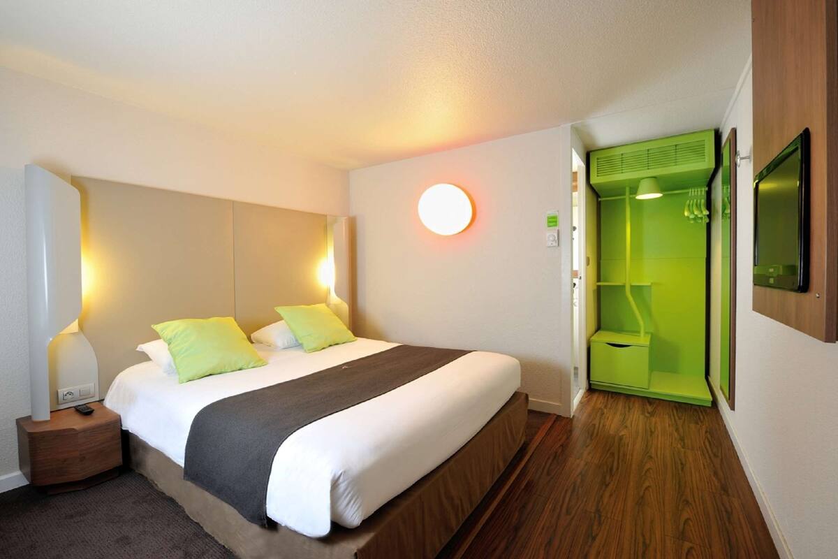 Ein Hotelzimmer mit einem Bett, einem Nachttisch und einem grünen Kleiderschrank.