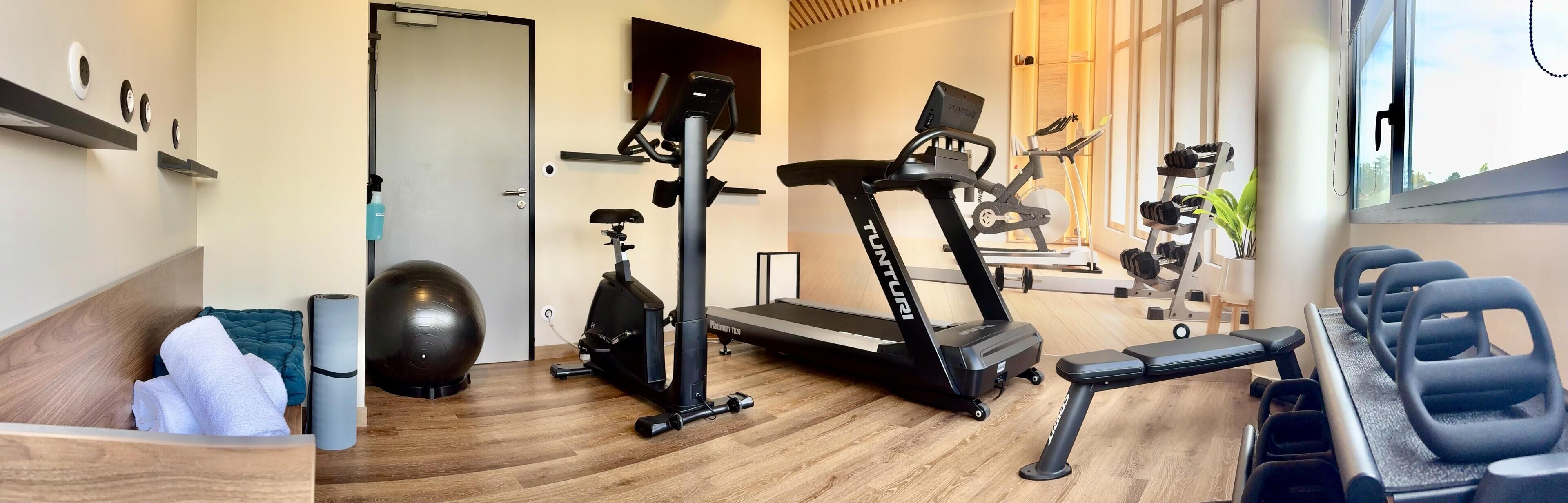 A home gym with a treadmill, exercise bike, and weights.