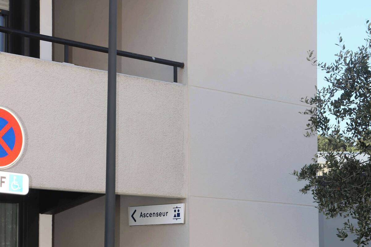 A building with a no parking sign, an exit sign, and a directional sign to the concierge.